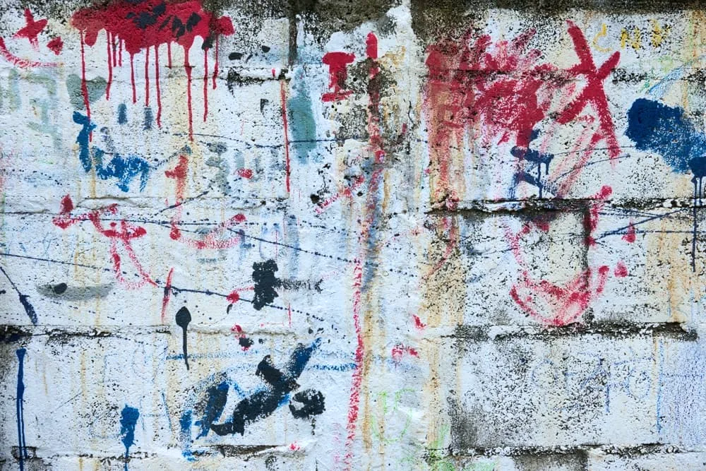 A wall covered in graffiti with red, blue, and white spray paint.