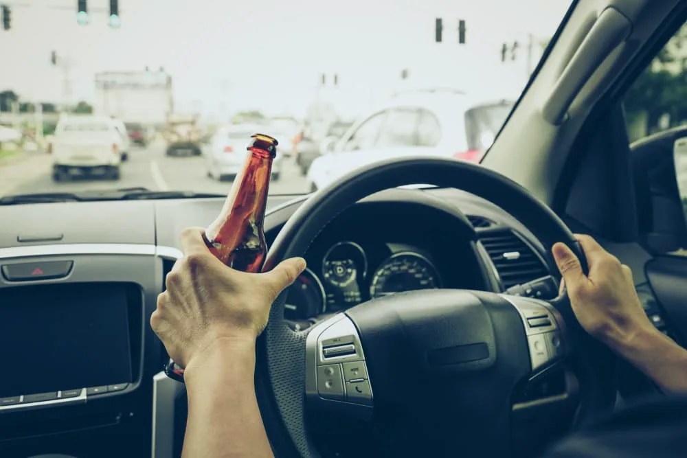 A driver holding alcoholic bottle while driving / Drunk driving
