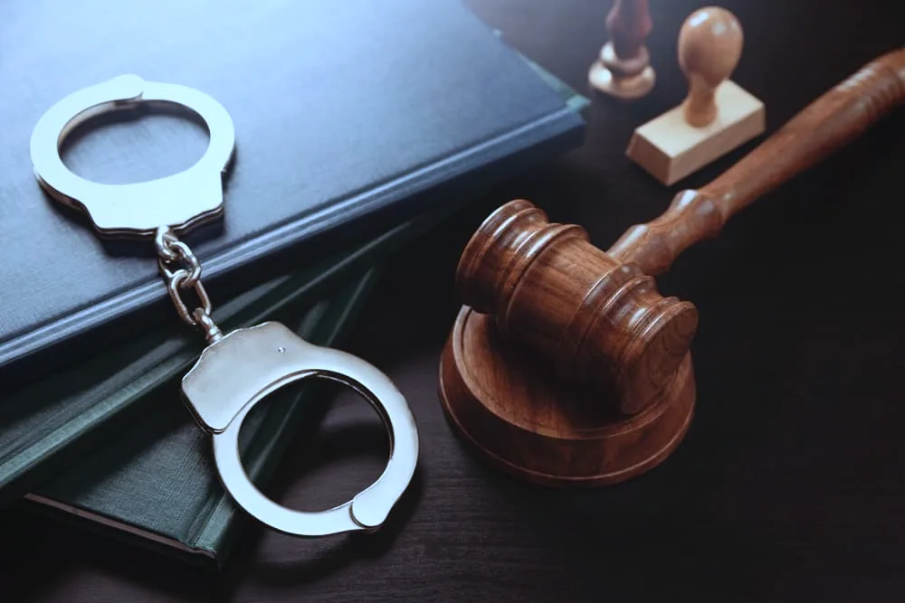 Arrest concept. Metal handcuffs near judge gavel.